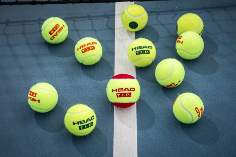 Multiple HEAD tennis balls on court.