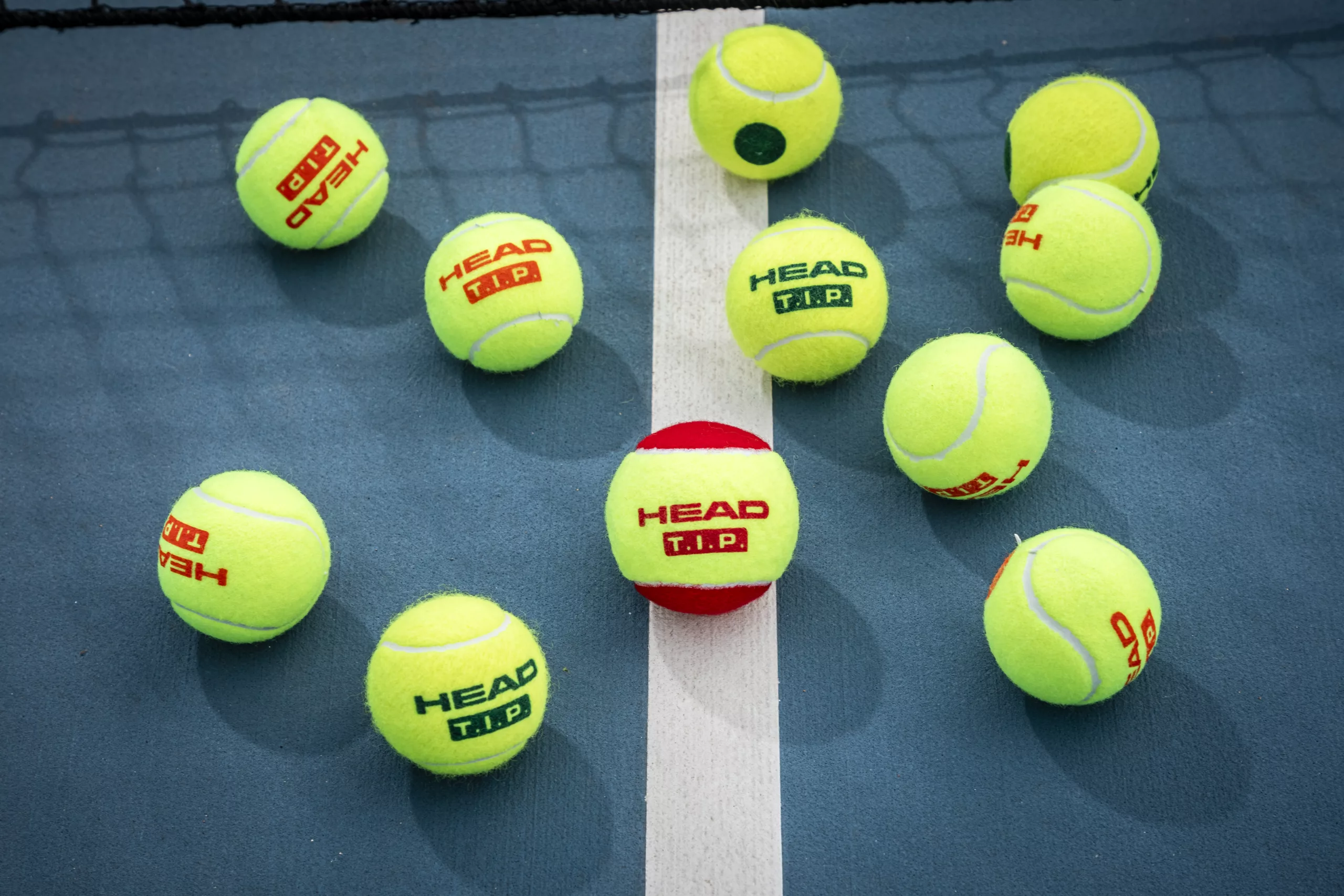 Multiple HEAD tennis balls on court.