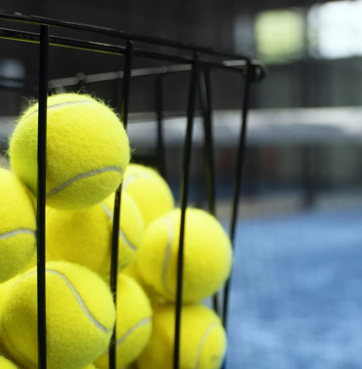 Tennis balls in a basket on a court at Bolton Arena