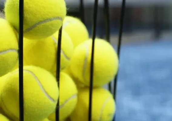 Tennis balls in a basket on a tennis court at Bolton Arena