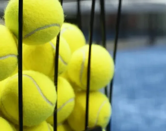 Tennis balls in a basket on a tennis court at Bolton Arena