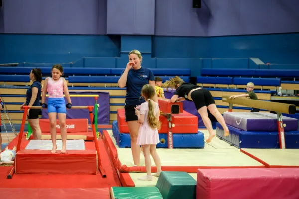 Member of gymnastics team speaking with gymnastics camp participant