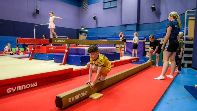 Active Bolton Gymnastics coach overseeing balance beam work during holiday camps