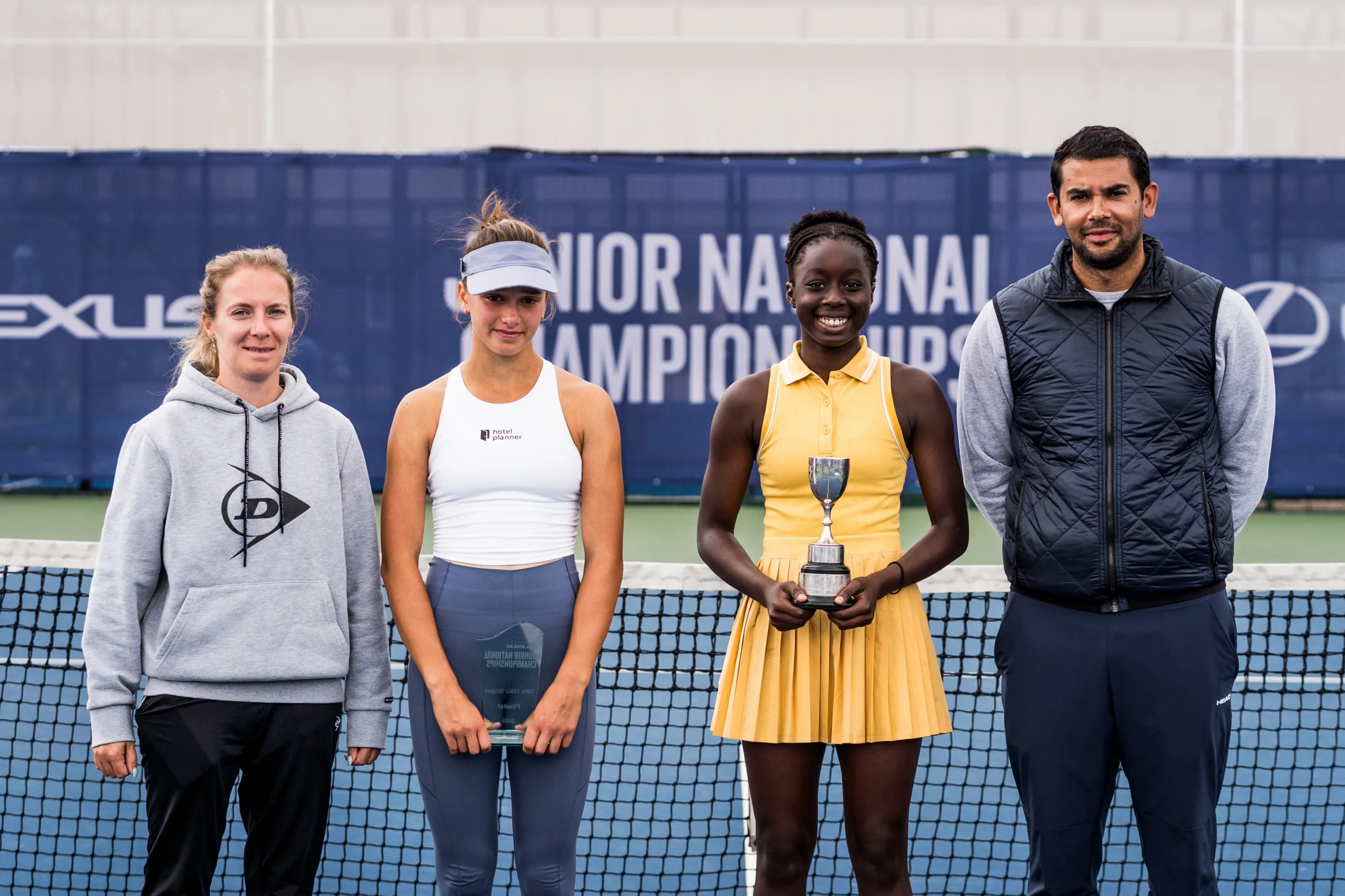tennis participants pose for a picture with a trophy