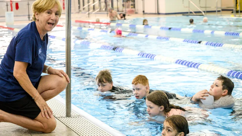 Swimming teacher on poolside teaching Children at aquatics training centre, Horwich Leisure Centre