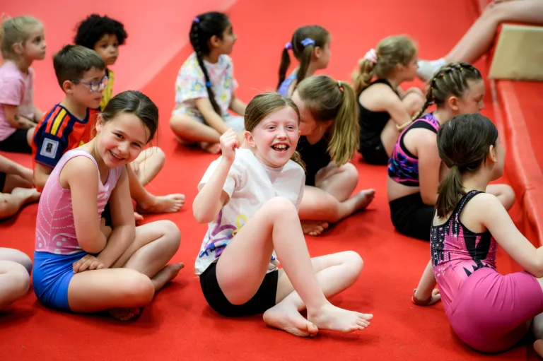 Children sat on floor during gymnastics holiday camp.