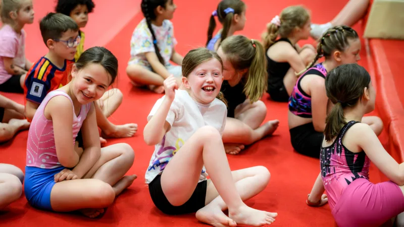 Children sat on floor during gymnastics holiday camp.
