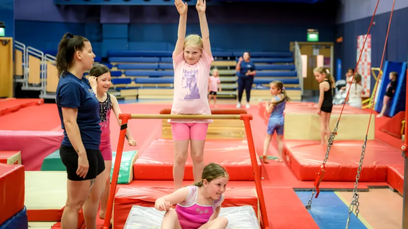 Girls using gymnastics apparatus during gymnastics camp