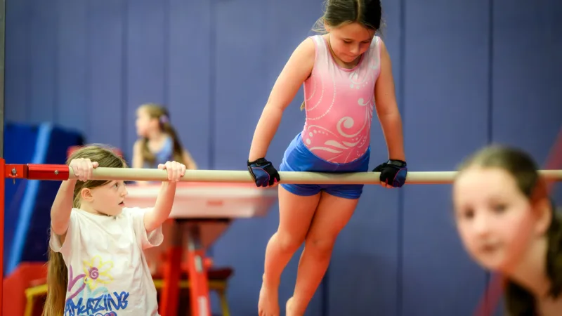 Girls using gymnastics bar at gymnastics camp at Active Bolton Arena