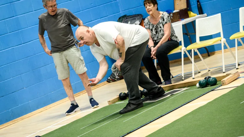 Man bending down to deliver bowls at Active Bolton Horwich