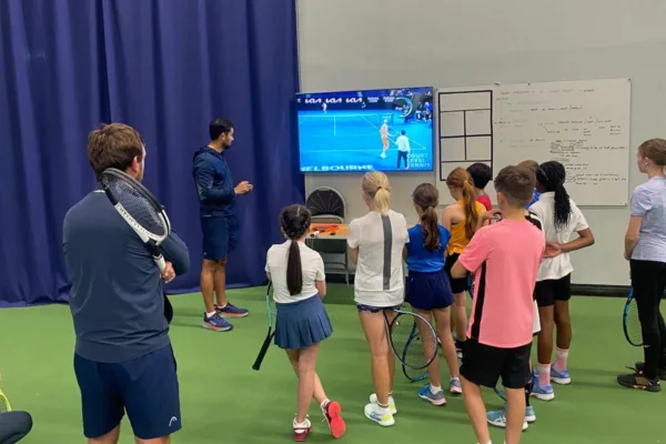 Performance squads children stood watching TV on tennis court