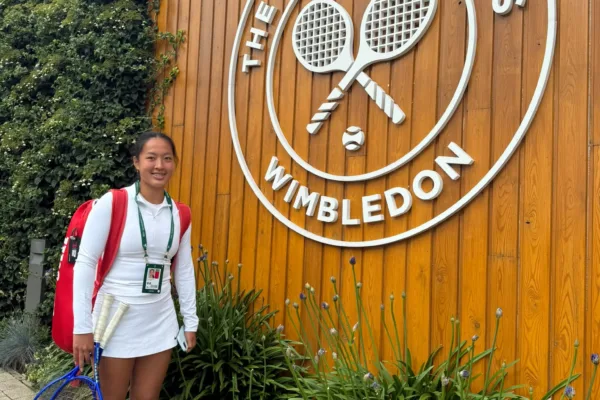 Annabel Wong stood in front of Wimbledon logo at Junior Wimbledon