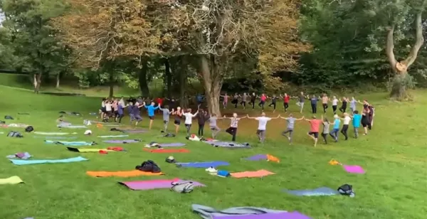 People stood holding hands surrounding a tree at final park yoga 2026 session